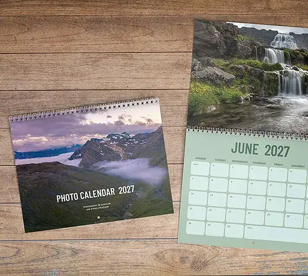 Een fotokalender van een jaar met prachtige avonturen 2027, met de cover en de juni-pagina over de waterval.