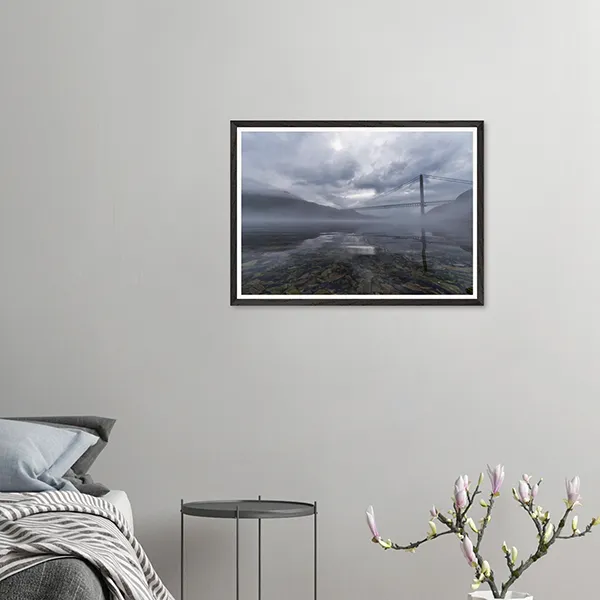 Kvalsund Bridge in northern Norway surrounded by sea mist and dramatic clouds reflected in calm Arctic water.